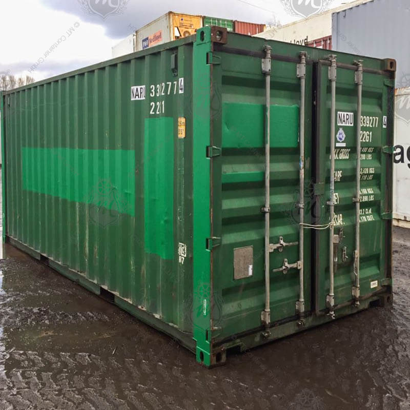 Der grüne 20-Fuß-Seecontainer NARU 339277-4 steht auf nassem Boden. Er hat zwei große, verriegelte Türen an der Vorderseite und trägt mehrere Beschriftungen.